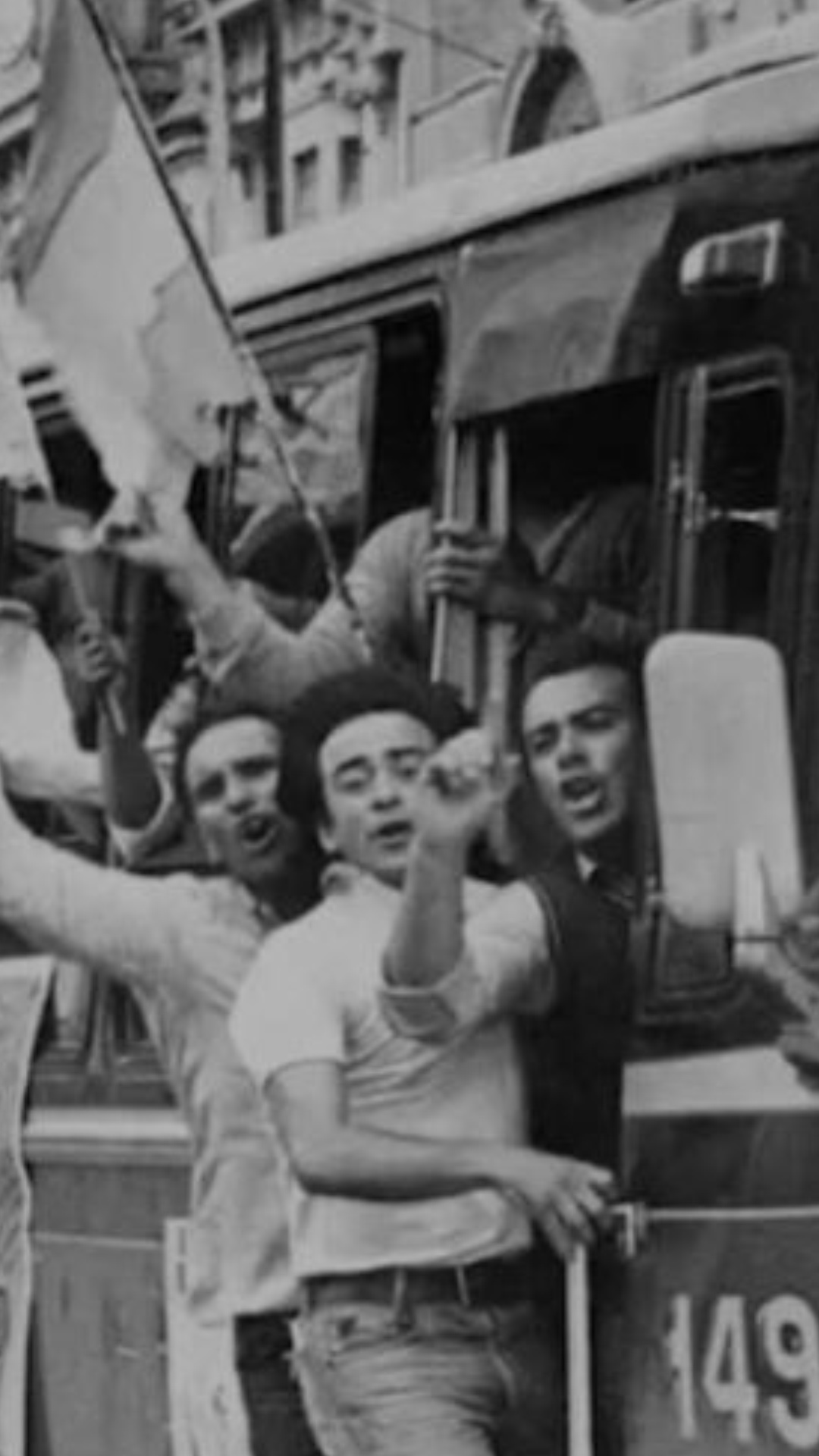 Colectivo de la línea 149, lleno de jóvenes con banderas argentinas yendo votar. Hay jóvenes colgados de las ventanas y puertas. 