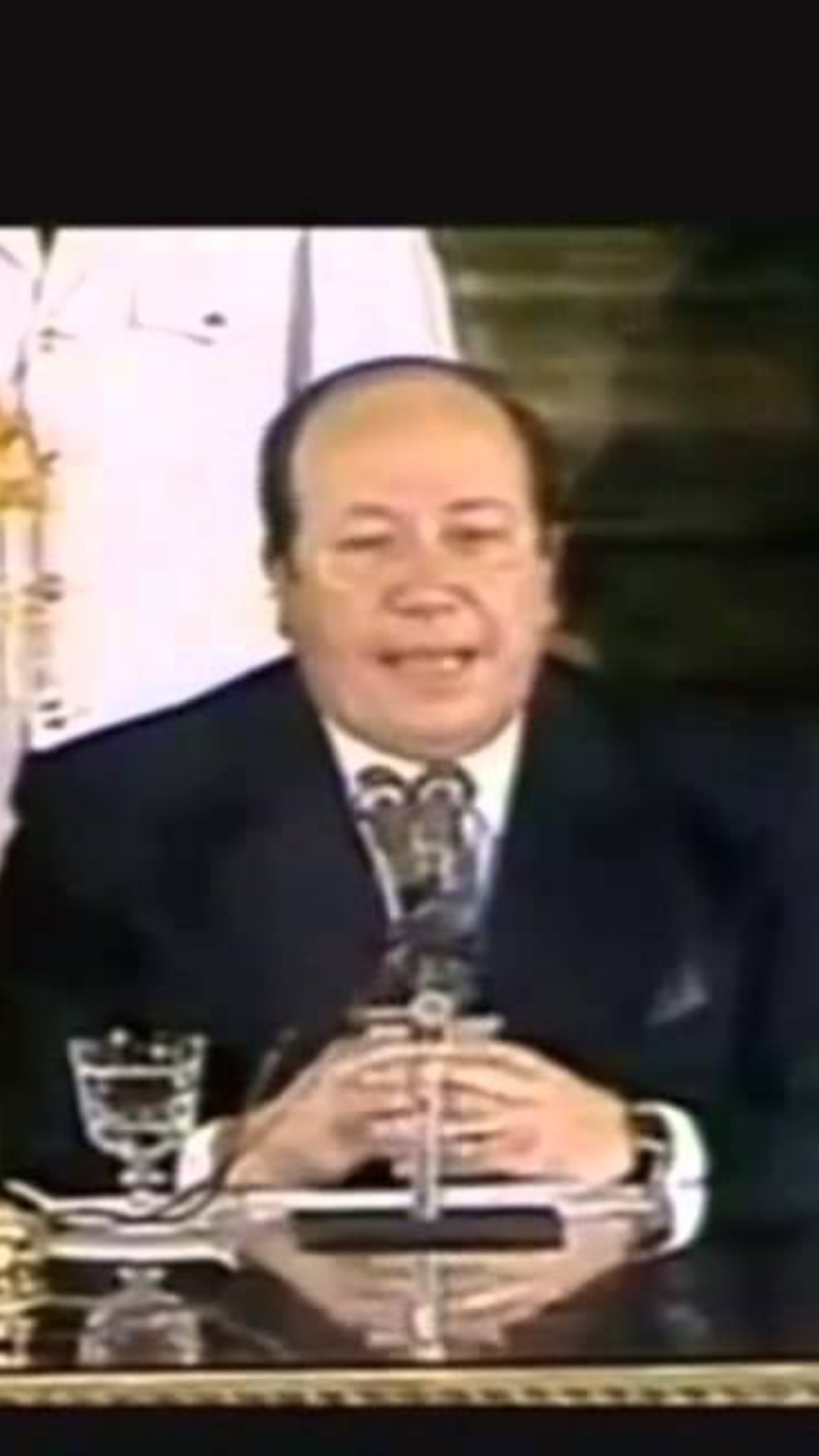 Hay tres personas sentadas frente a la foto en el palacio presidencial. A la izquierda: Carlos Menem, presidente de esa época. En el centro Roberto José Dromi ministro de obras y servicios públicos, quien parece estar hablando y a la derecha Erman González, ministro de trabajo y seguridad social de ese entonces. 