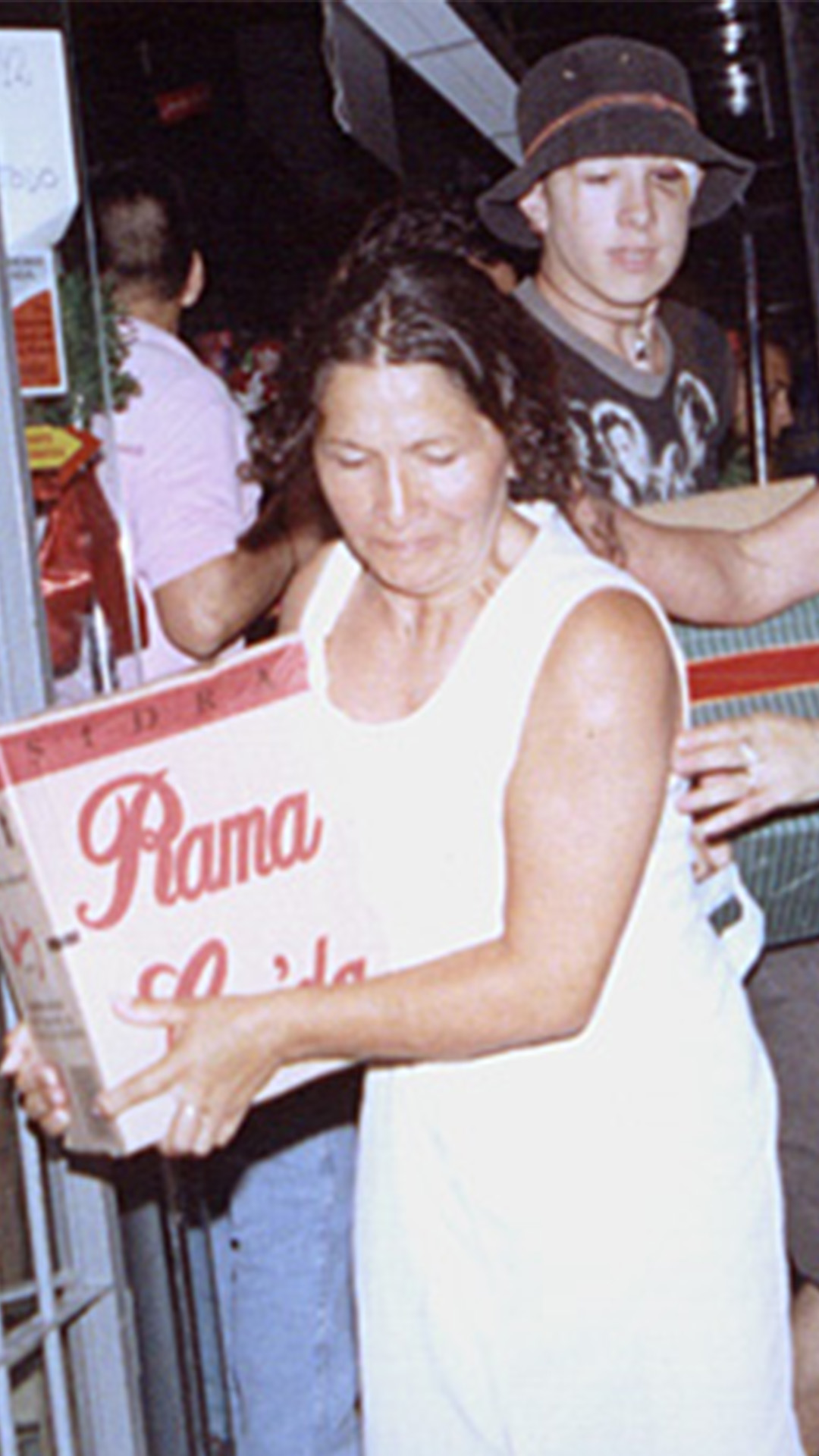 Dos mujeres saliendo de un supermercado con una caja de sidra. Atrás de ellas sale un jóven con otra caja.