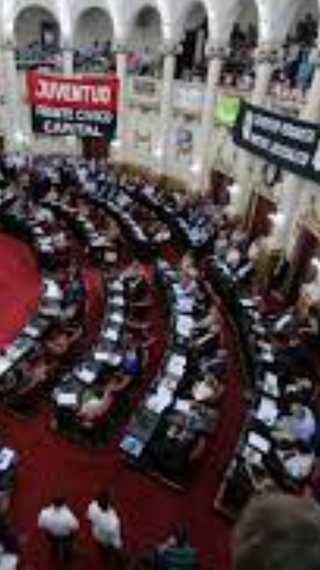 El recinto de la Honorable Cámara de Senadores de la Nación desde arriba, en el debate de la Ley de Voto Jóven. Sobre los balcones se asoman banderas de diferentes partidos políticos.