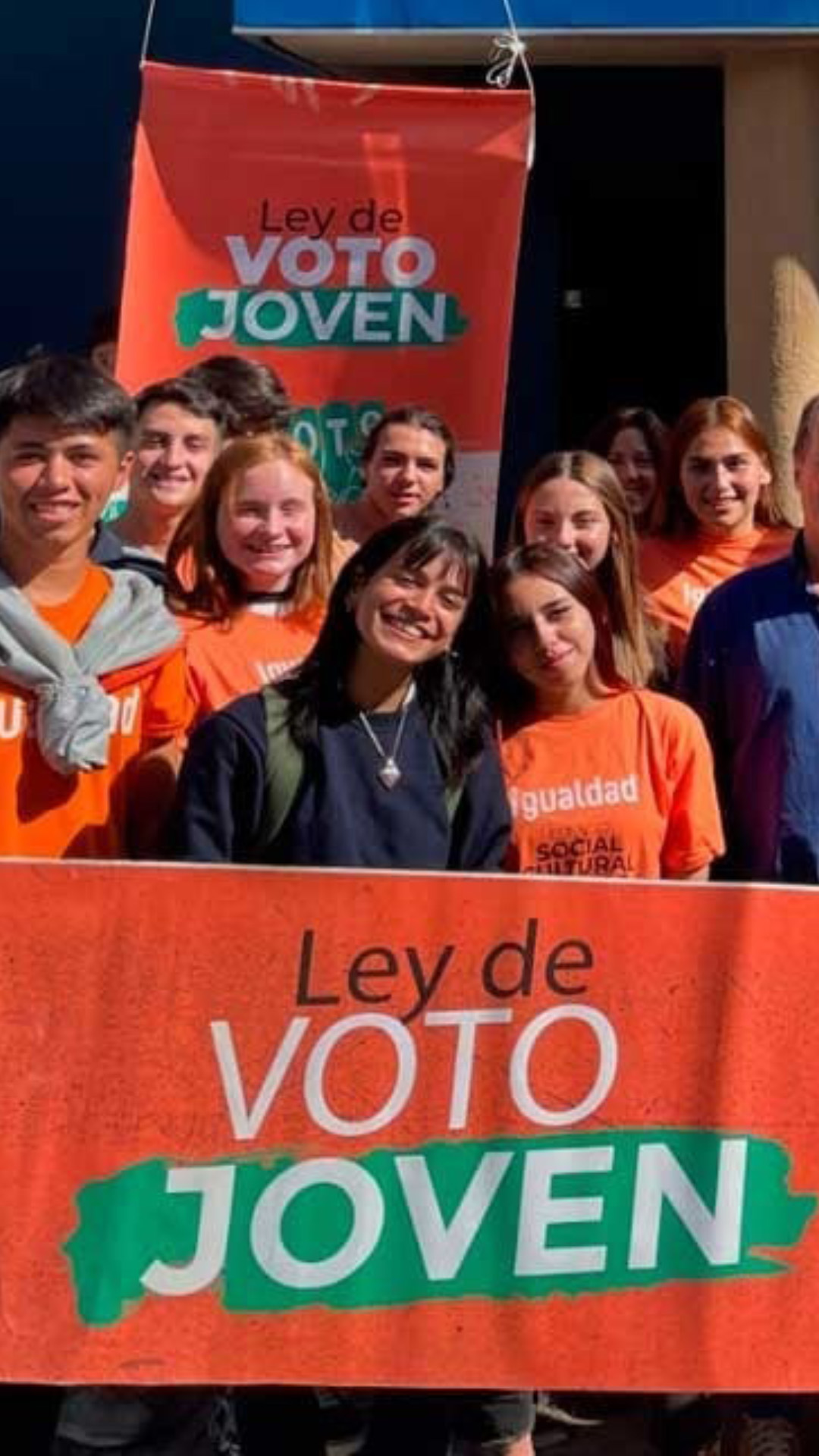 Un grupo de jóvenes posa con el cartel Ley de voto jóven. En el fondo alguien levanta una urna. En el frente una chica levanta un cartel con la leyenda “merecemos votar, voto jóven”